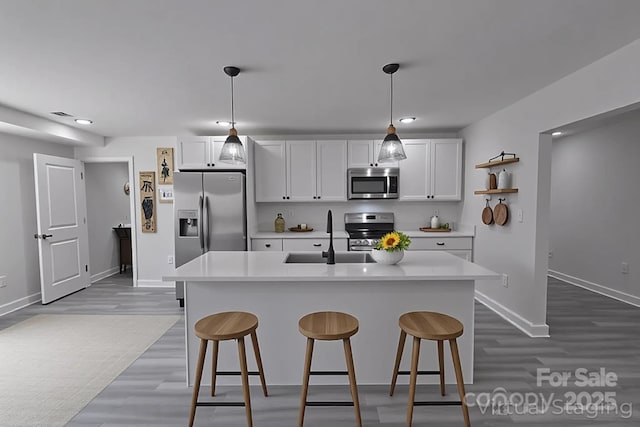 116 11th St, Spencer, NC 28159 - kitchen featuring appliances with stainless steel finishes, dark wood-style flooring, light countertops, a kitchen bar, and recessed lighting