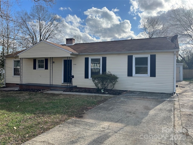 single story home with driveway, a chimney, and a front yard