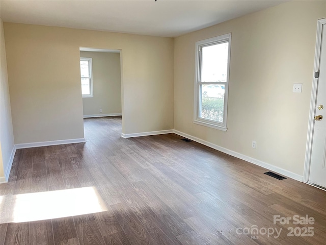 spare room with visible vents, baseboards, and wood finished floors