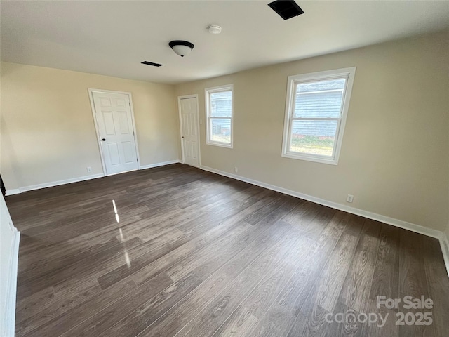 spare room featuring baseboards and dark wood finished floors