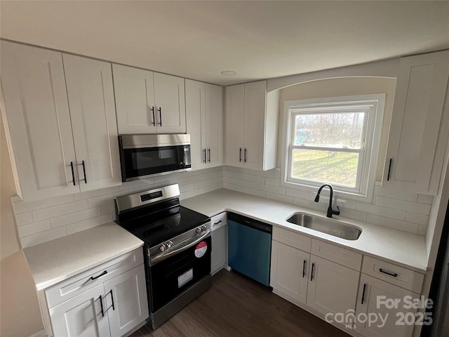 kitchen featuring appliances with stainless steel finishes, dark wood-type flooring, a sink, and white cabinetry