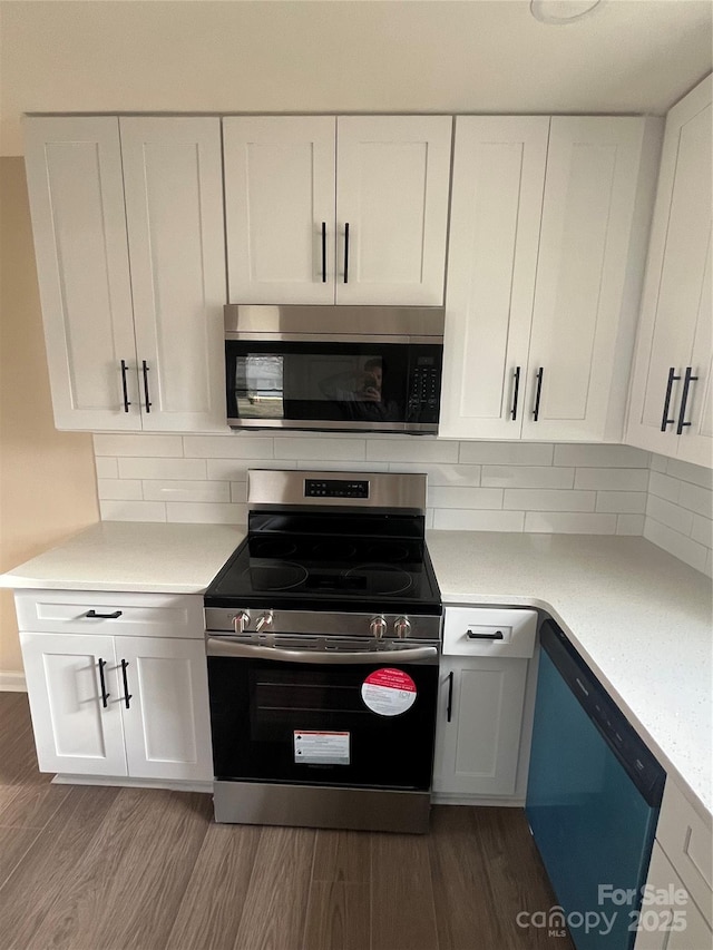 kitchen with dark wood-type flooring, white cabinetry, stainless steel appliances, and light countertops