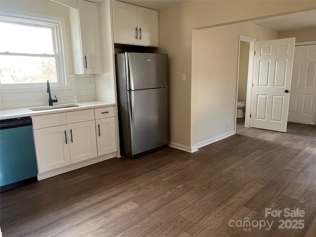 kitchen featuring dark wood finished floors, freestanding refrigerator, white cabinets, a sink, and dishwashing machine