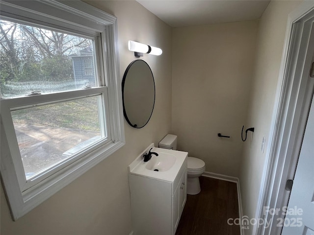 half bathroom featuring vanity, plenty of natural light, wood finished floors, and toilet