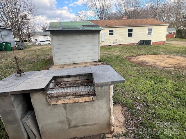 view of storm shelter featuring cooling unit, a yard, and an outbuilding