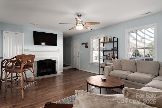 living area featuring a wealth of natural light, visible vents, a fireplace, and wood finished floors