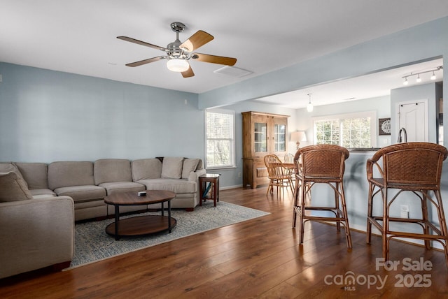 living area featuring ceiling fan, hardwood / wood-style floors, visible vents, and baseboards