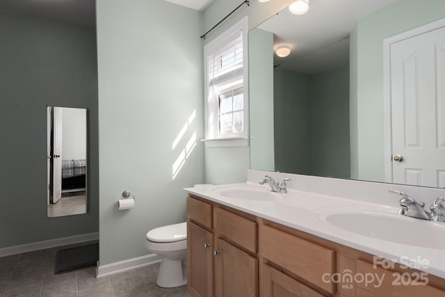 bathroom featuring double vanity, tile patterned flooring, a sink, and toilet