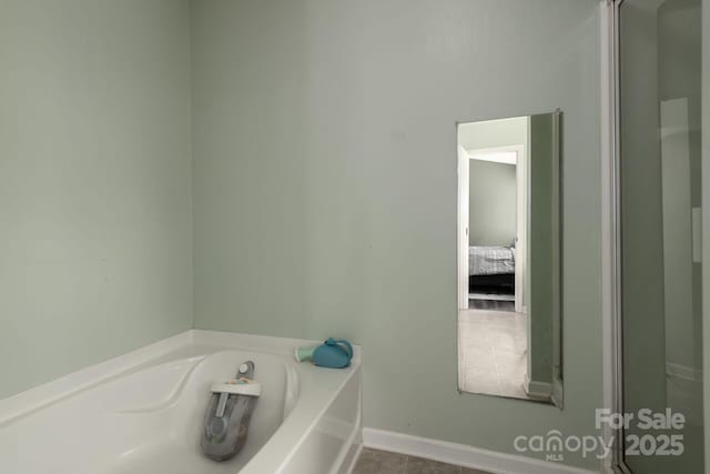 ensuite bathroom featuring baseboards, a garden tub, and connected bathroom