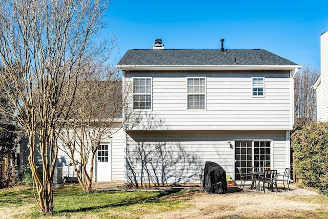 back of house featuring a patio, a chimney, and a lawn