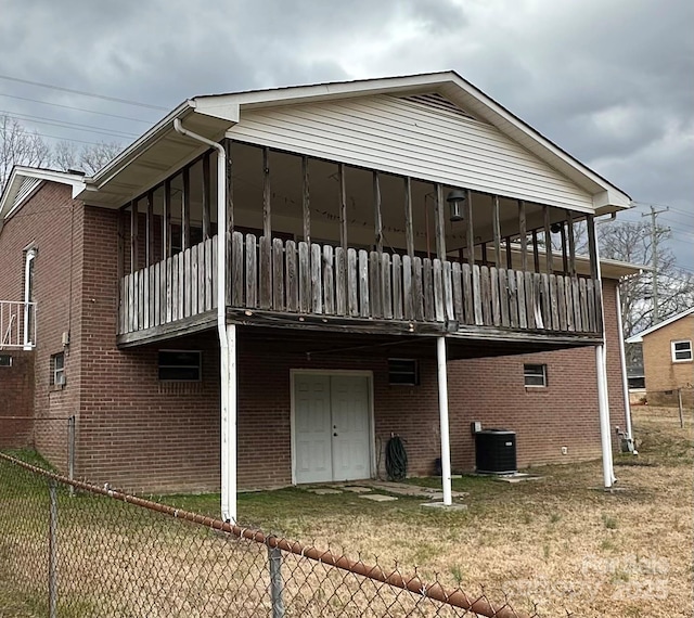 rear view of property featuring central AC, brick siding, a lawn, and fence