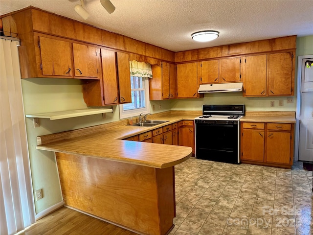 kitchen with range with gas cooktop, brown cabinets, light countertops, under cabinet range hood, and a sink