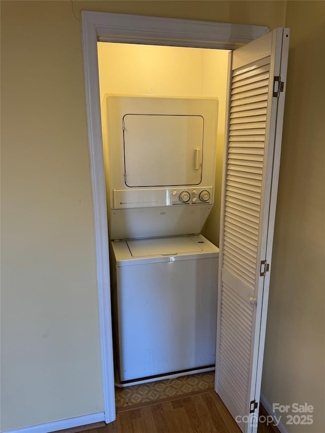 laundry room featuring stacked washer and dryer, laundry area, and dark wood-style flooring