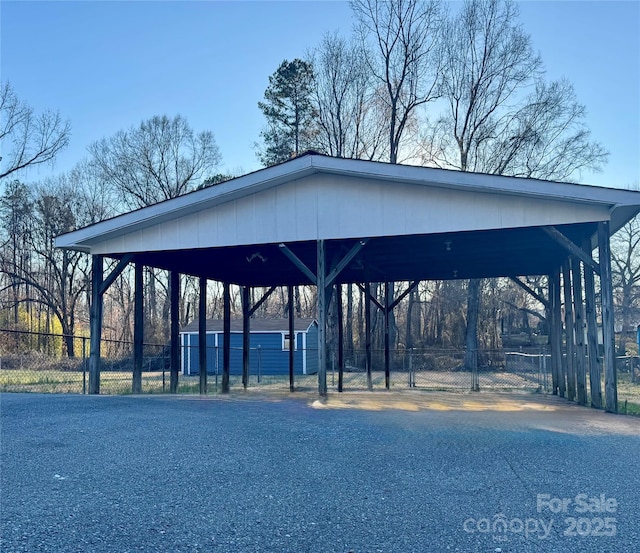 view of community with fence, aphalt driveway, and a carport