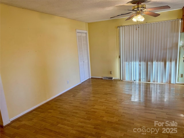 spare room featuring visible vents, a textured ceiling, baseboards, and wood finished floors