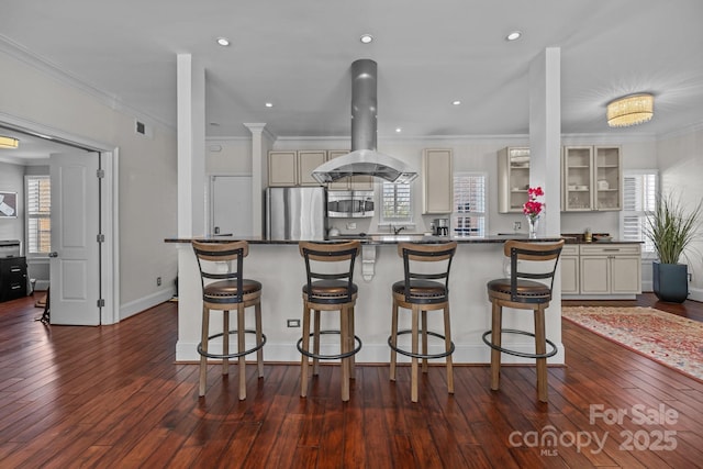 kitchen with dark countertops, island range hood, ornamental molding, and freestanding refrigerator