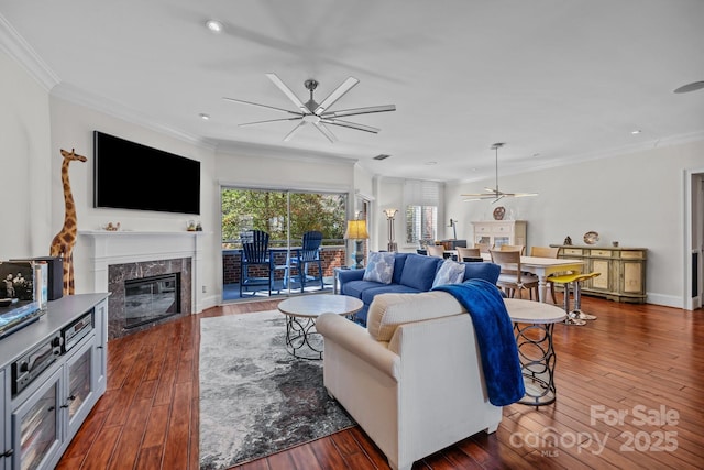 living area featuring ceiling fan, ornamental molding, hardwood / wood-style floors, and a high end fireplace