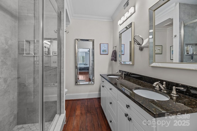 full bath with ornamental molding, a stall shower, a sink, and wood finished floors