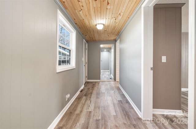 hall featuring baseboards, wood finished floors, and wooden ceiling