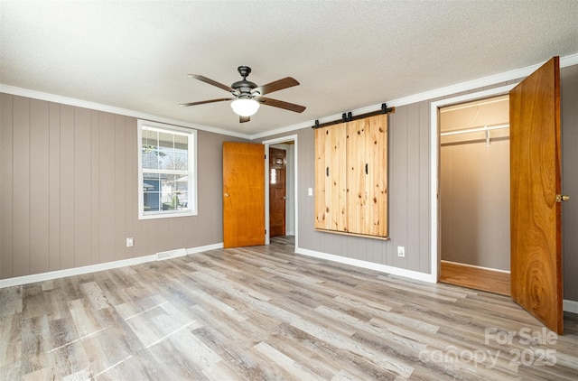 unfurnished bedroom featuring visible vents, a textured ceiling, wood finished floors, crown molding, and baseboards