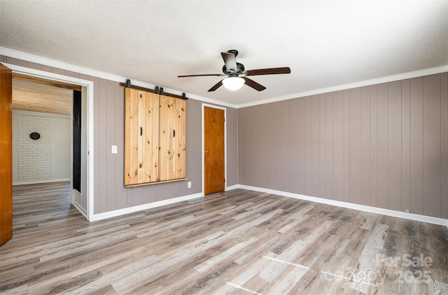 spare room with crown molding, baseboards, wood finished floors, a textured ceiling, and a ceiling fan