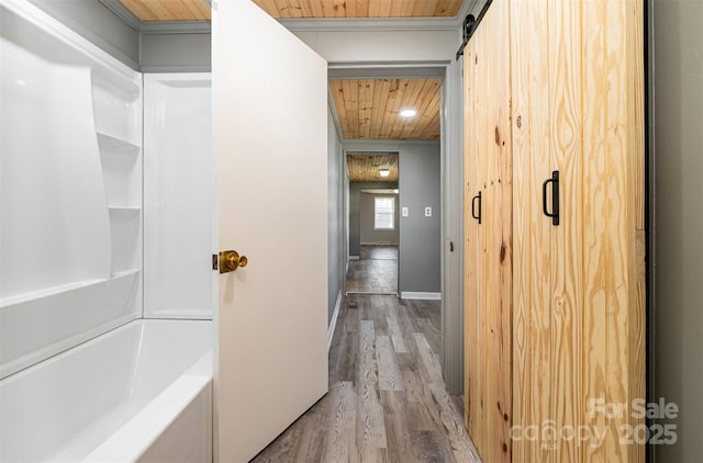 hall with light wood-type flooring, ornamental molding, a barn door, wooden ceiling, and baseboards