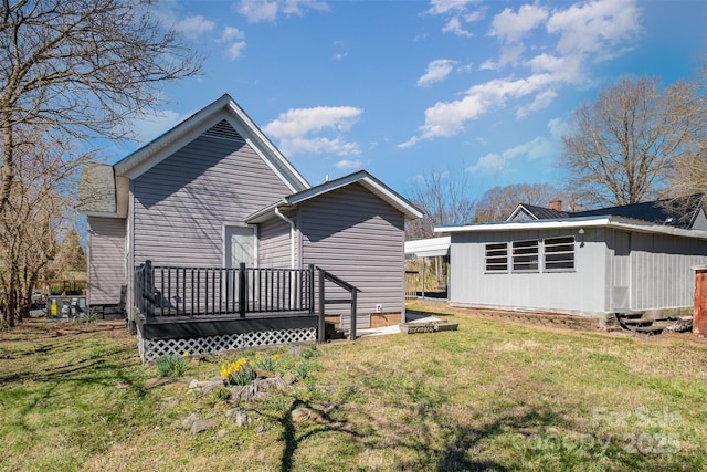 back of house featuring a wooden deck and a lawn