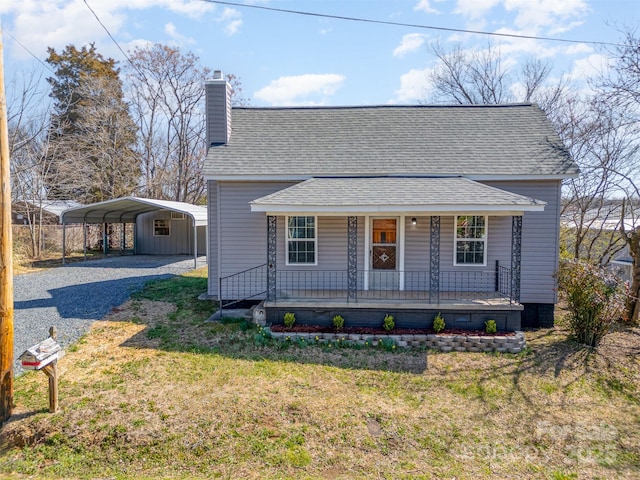 view of front of home featuring a front lawn, a porch, gravel driveway, a detached carport, and a shingled roof