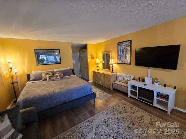 bedroom with a textured ceiling, baseboards, and wood finished floors