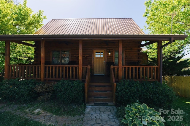 view of front facade with metal roof, covered porch, and log exterior