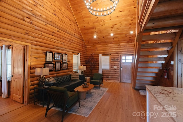 living area with high vaulted ceiling, rustic walls, a notable chandelier, and light wood finished floors