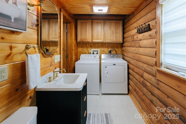 laundry room featuring log walls, washing machine and clothes dryer, cabinet space, a sink, and wooden ceiling