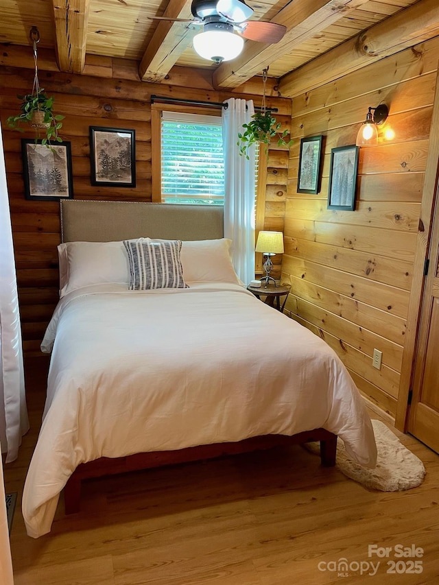 bedroom featuring beamed ceiling, wooden ceiling, wood finished floors, and log walls