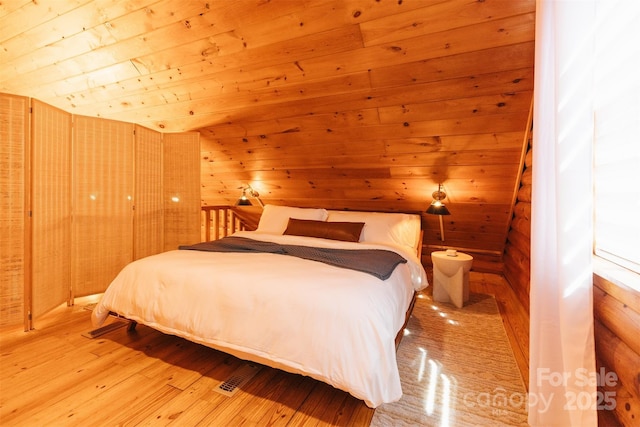 bedroom featuring wood ceiling, wood walls, and light wood-style flooring