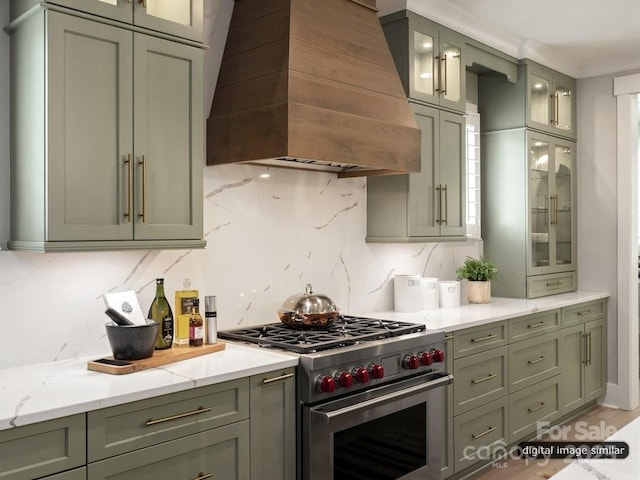 kitchen featuring decorative backsplash, light stone counters, custom exhaust hood, and high end stainless steel range