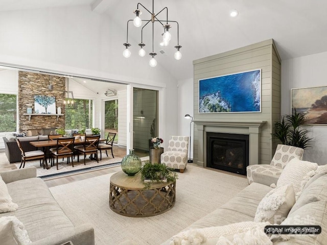 living area featuring high vaulted ceiling, wood finished floors, a notable chandelier, and a glass covered fireplace