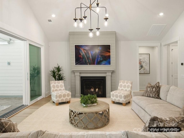 living area featuring vaulted ceiling, a fireplace, wood finished floors, and visible vents