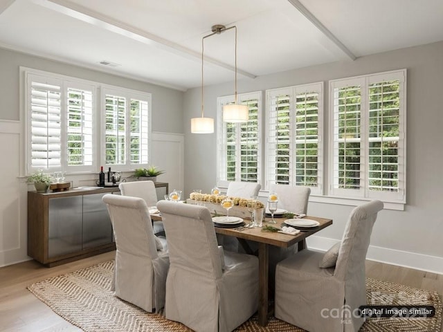 dining space with light wood finished floors, beam ceiling, visible vents, and baseboards