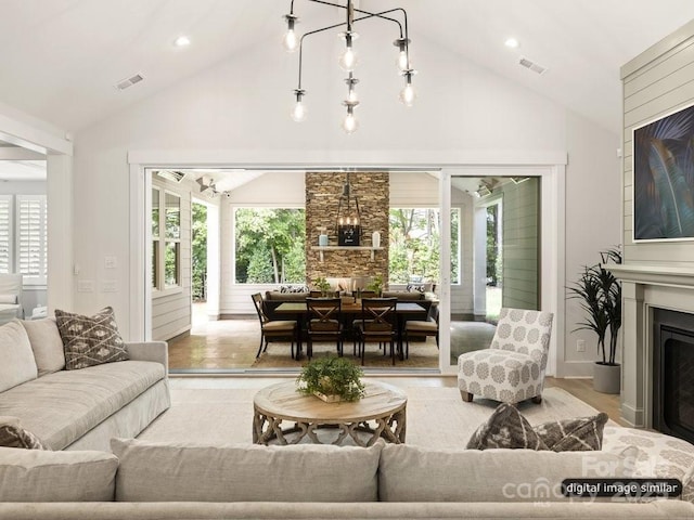 living area with vaulted ceiling, a fireplace, wood finished floors, and visible vents