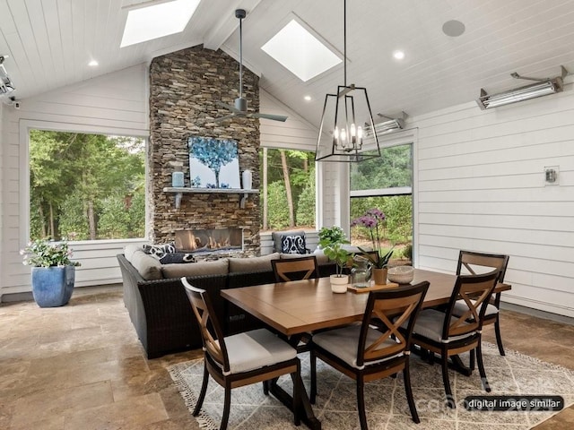 dining area with a stone fireplace, a skylight, and a wealth of natural light