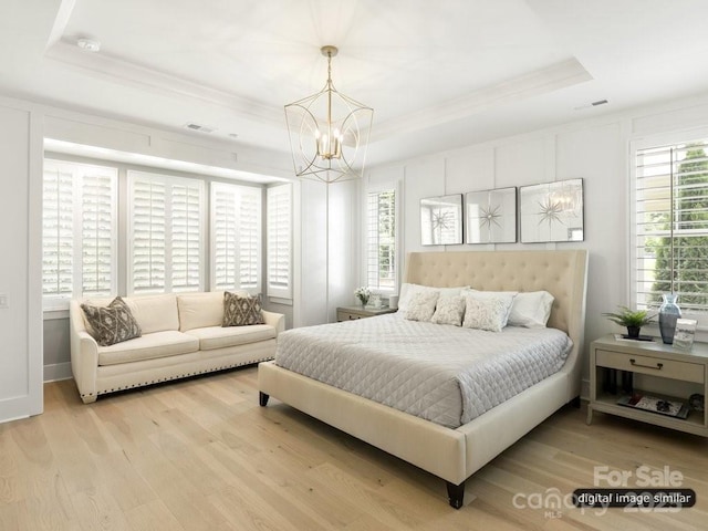 bedroom featuring a chandelier, a raised ceiling, and wood finished floors