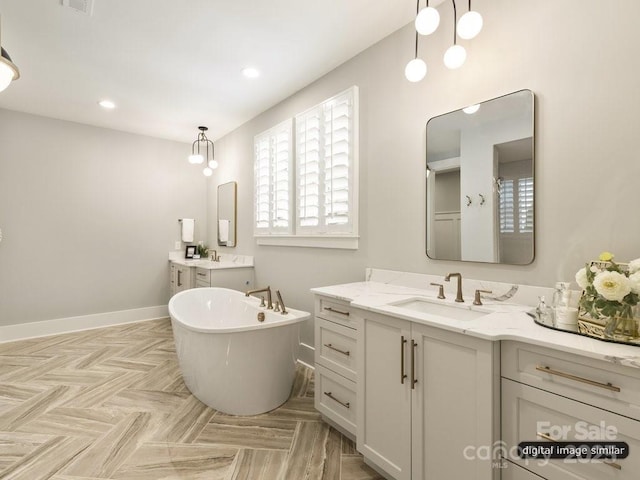 bathroom with plenty of natural light, a sink, a freestanding bath, and baseboards