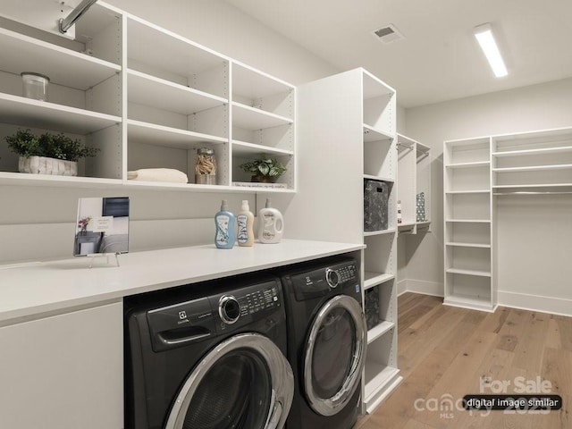 laundry area featuring laundry area, visible vents, light wood finished floors, and washing machine and clothes dryer