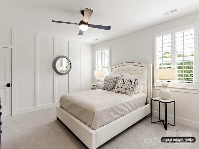 bedroom with carpet floors, visible vents, a decorative wall, ceiling fan, and baseboards