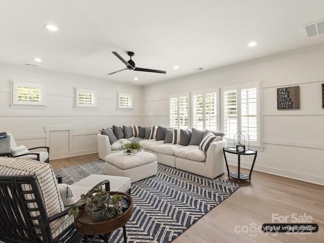 living area with ornamental molding, wood finished floors, visible vents, and recessed lighting