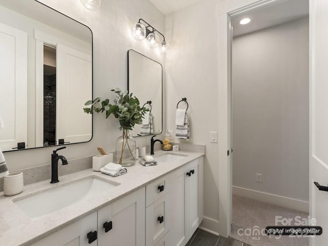 full bath with double vanity, a sink, and baseboards