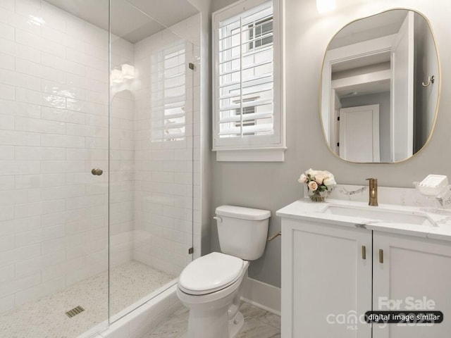 bathroom with marble finish floor, toilet, vanity, tiled shower, and baseboards