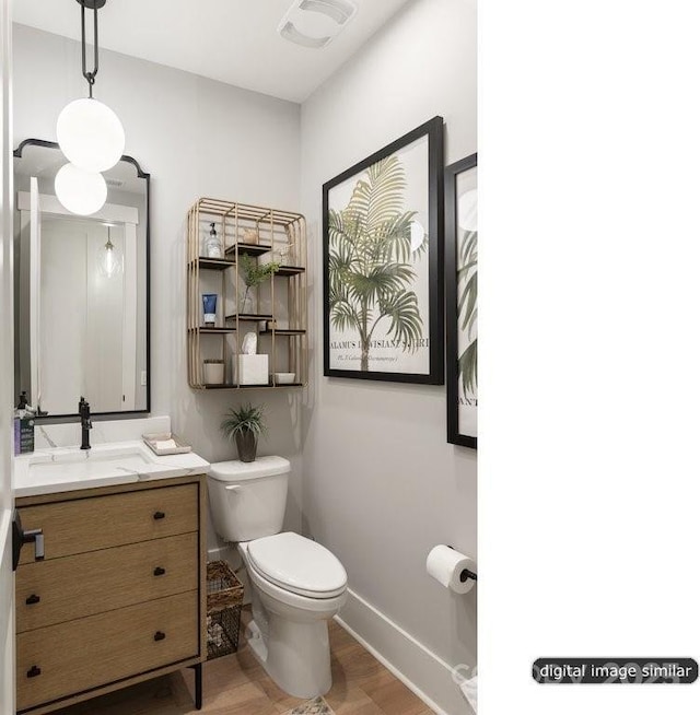 bathroom featuring toilet, wood finished floors, visible vents, vanity, and baseboards