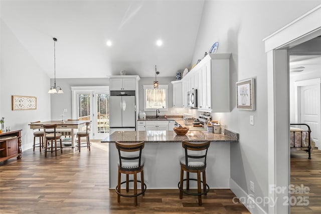 kitchen featuring stainless steel appliances, dark wood-type flooring, white cabinetry, a sink, and a peninsula