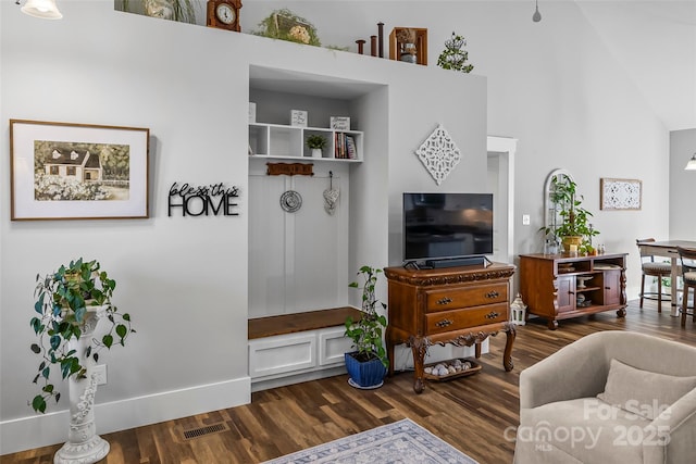 living room with dark wood-style floors, visible vents, high vaulted ceiling, and baseboards